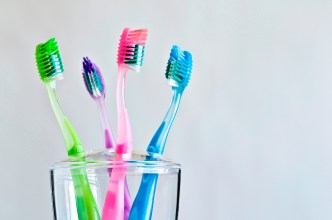 Four different colored toothbrushes in toothbrush holder.